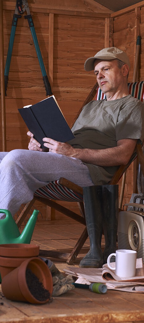 Man readingbook in garden shed